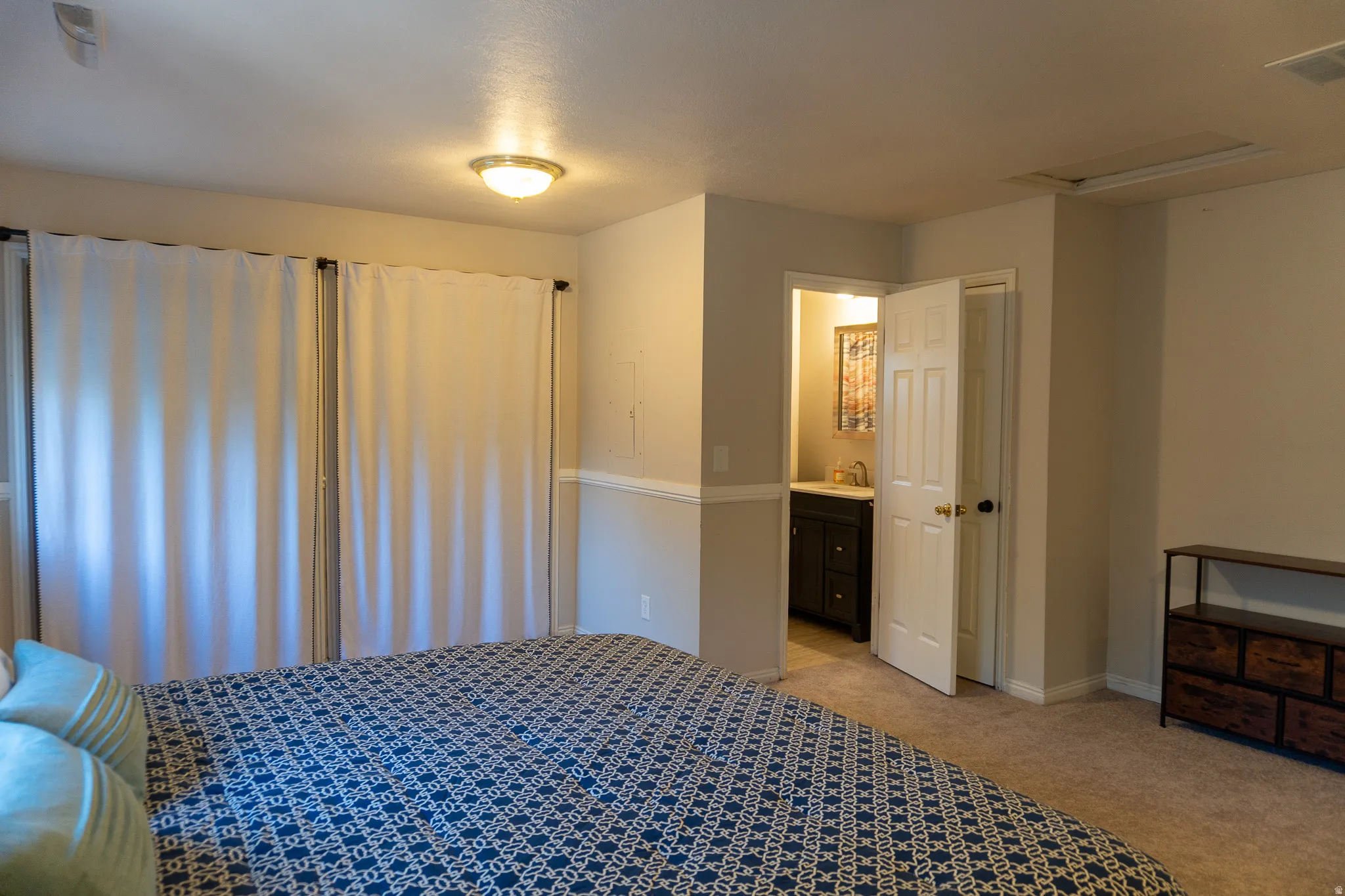 Bedroom featuring neutral carpet flooring and light-toned walls with chair rail molding