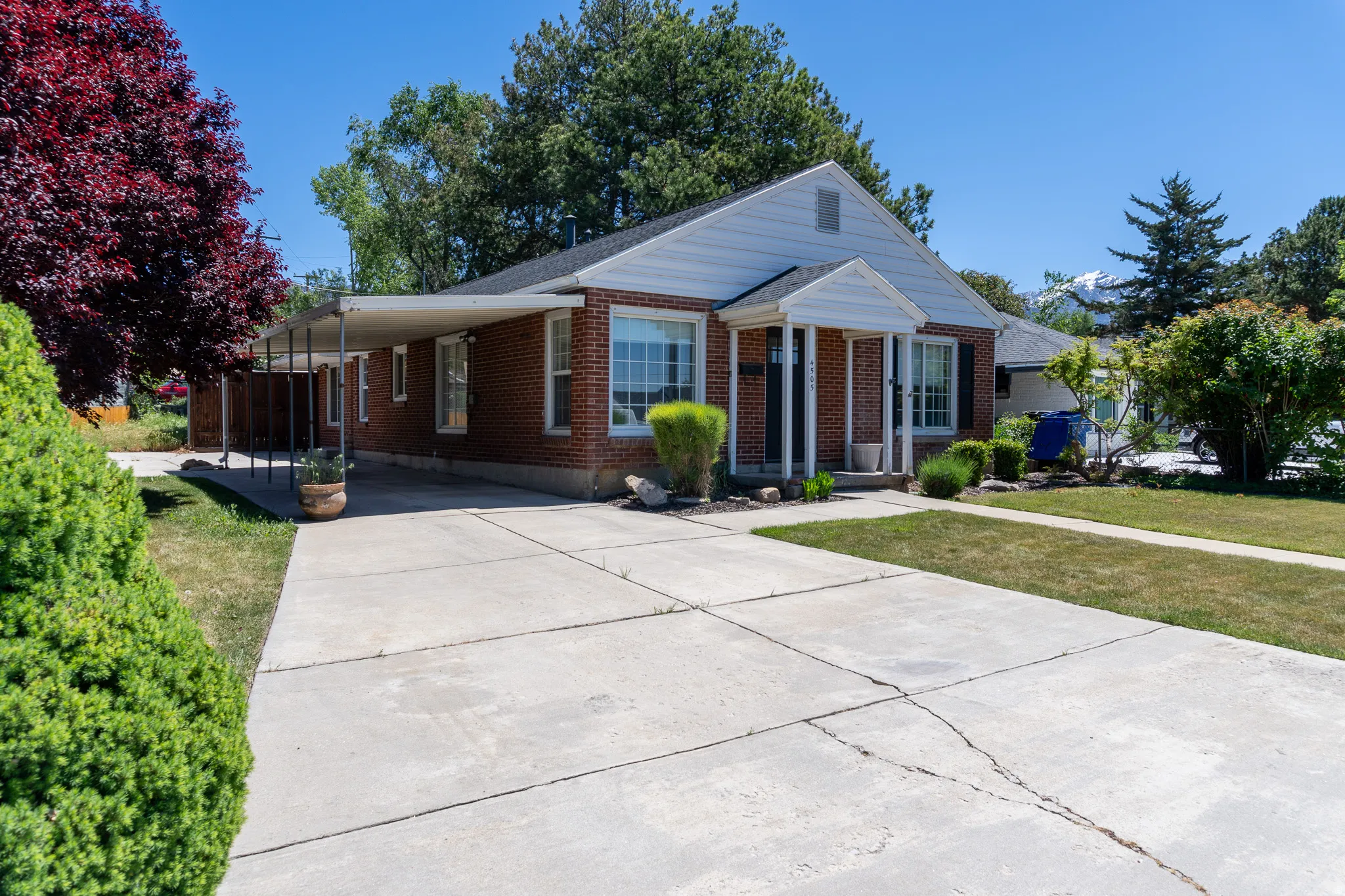 Brick exterior with white siding and black shutters, featuring a covered front porch with white columns