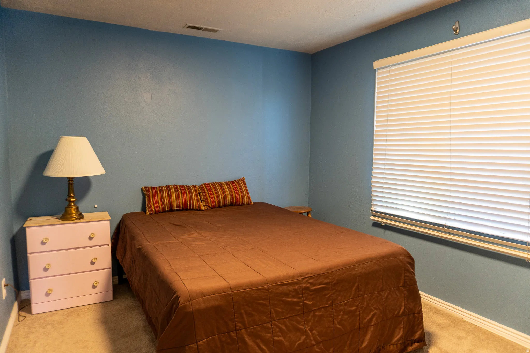 Room with blue-painted walls and a window featuring white horizontal blinds