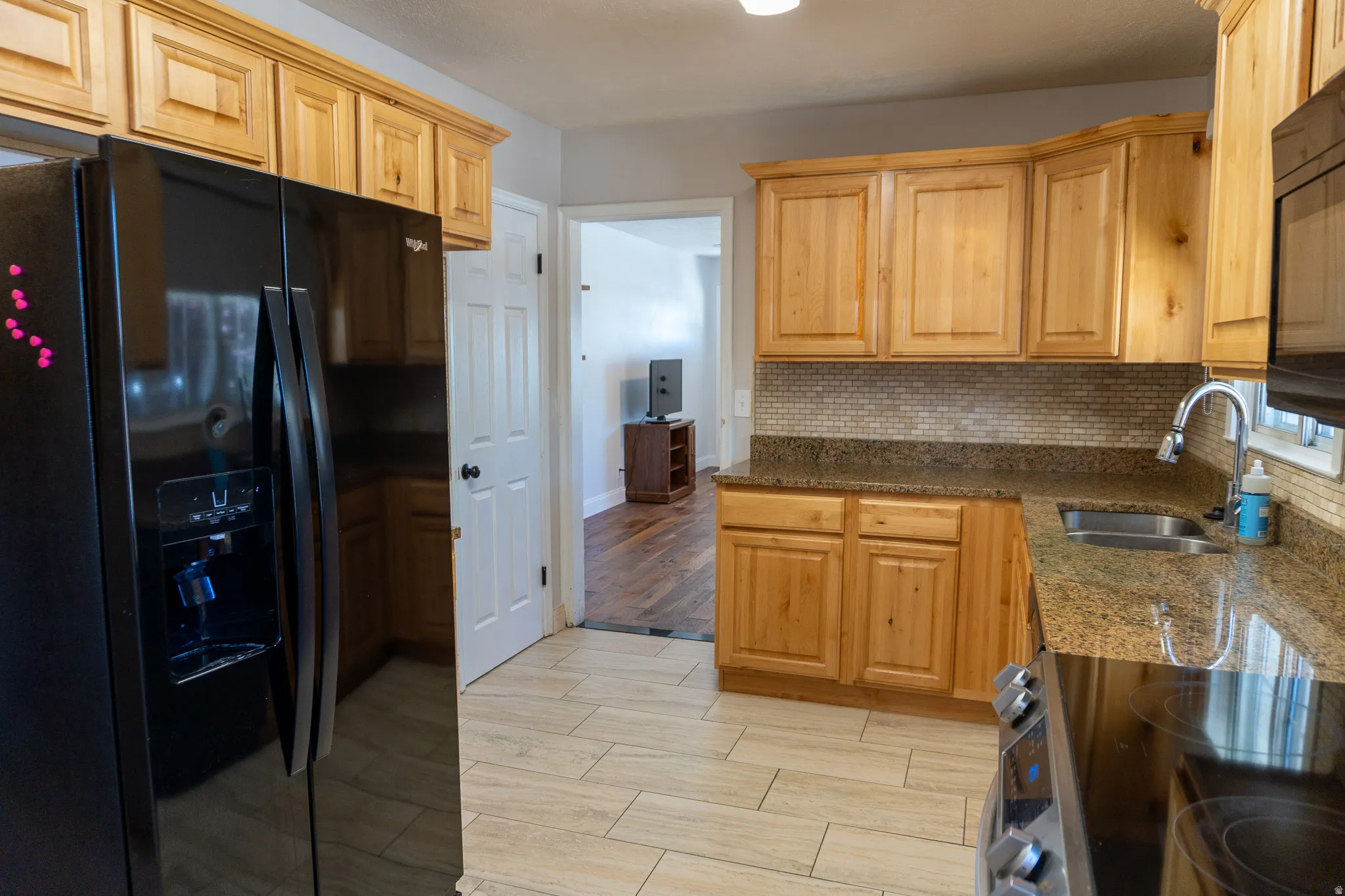 Kitchen featuring wood-finish cabinetry, granite-style countertops, and a full tile backsplash