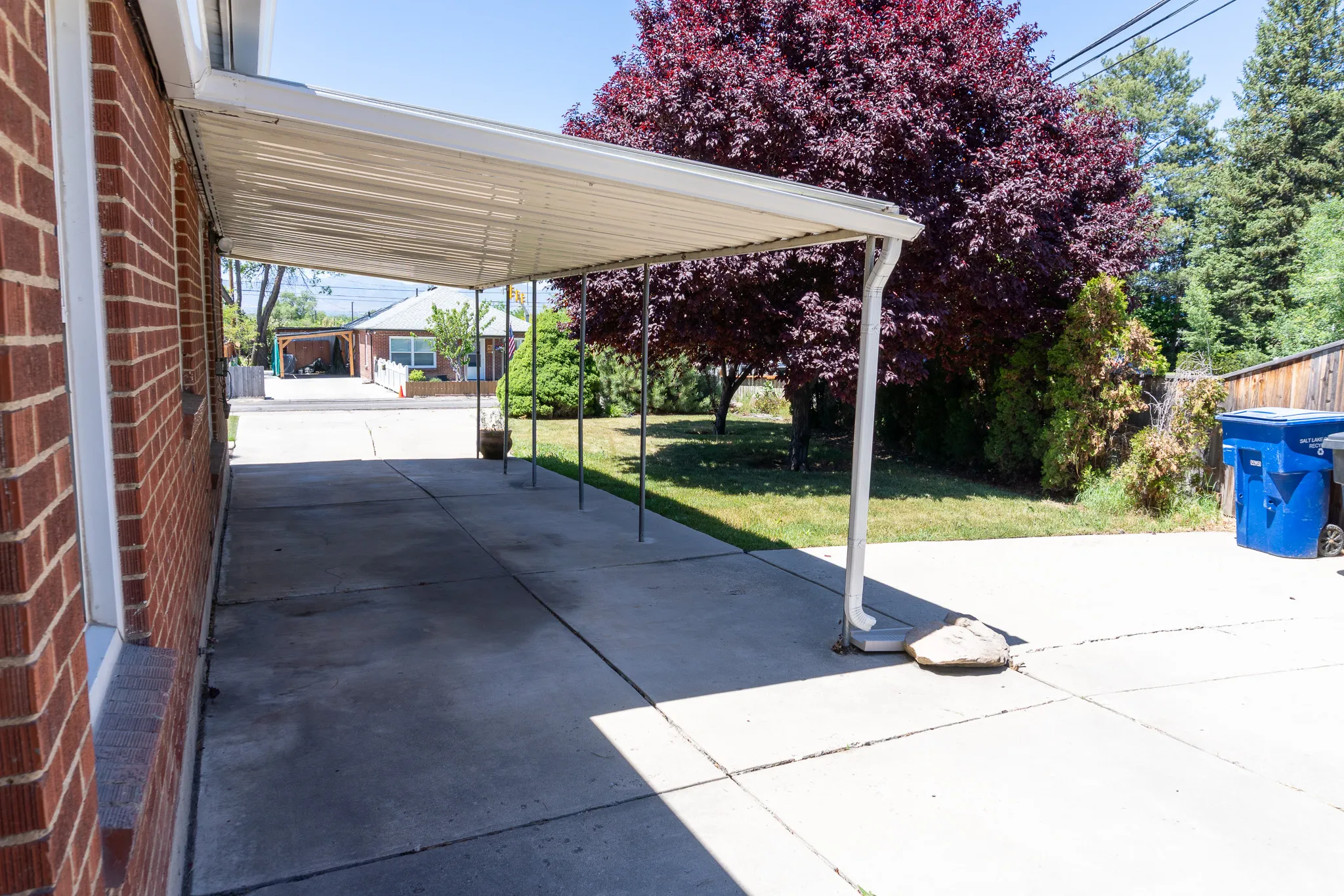 Covered concrete driveway alongside a brick exterior