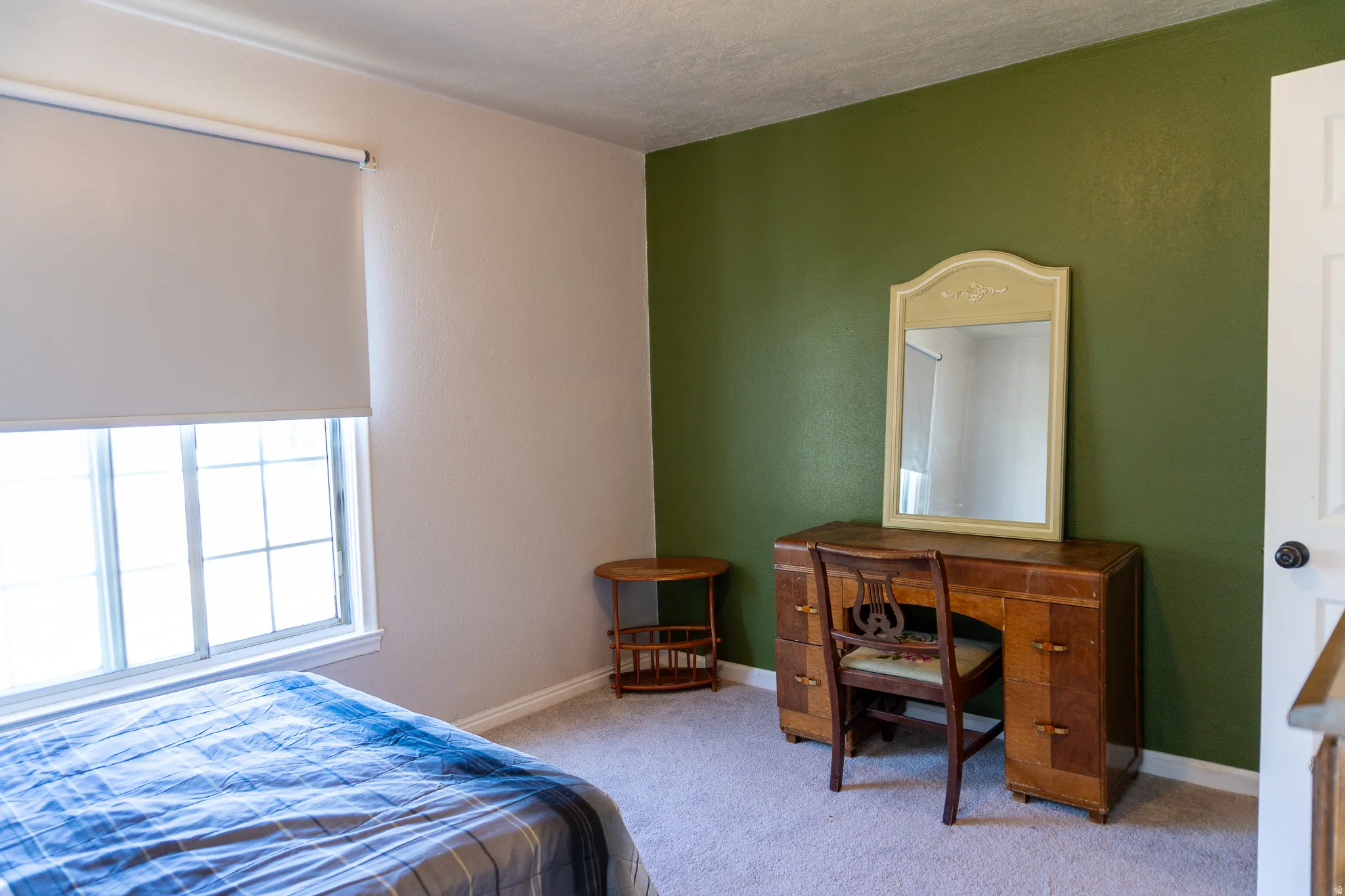 Carpeted room with a multi-pane window, roller shade, and light-toned walls complemented by an accent wall