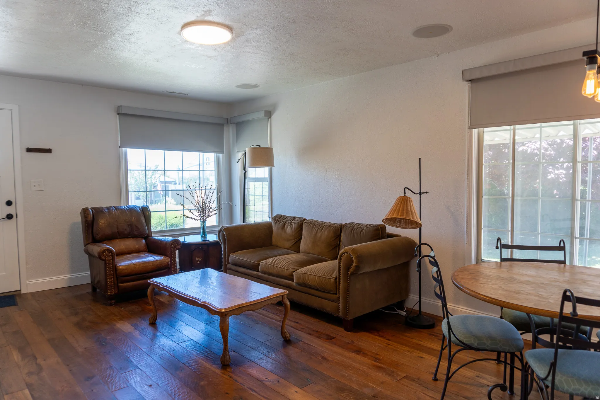 Open-concept living space with wood-finish flooring, white walls, and a flat-panel ceiling light