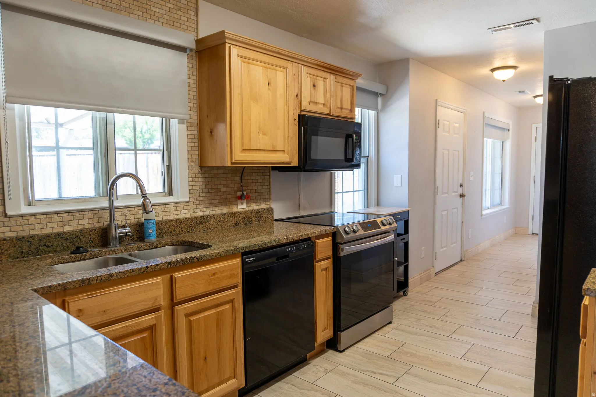 Kitchen featuring wood-finish cabinetry, stone countertops, and a full tile backsplash