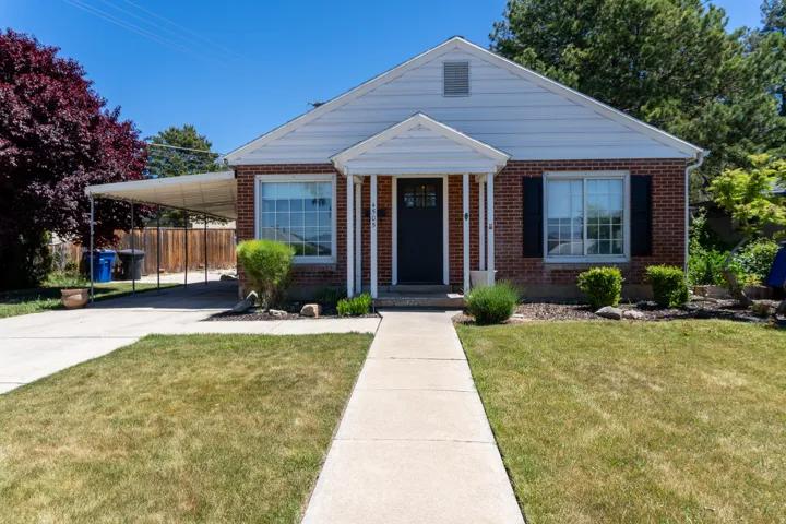 Brick and siding exterior featuring a covered carport, front porch entry, and a concrete walkway