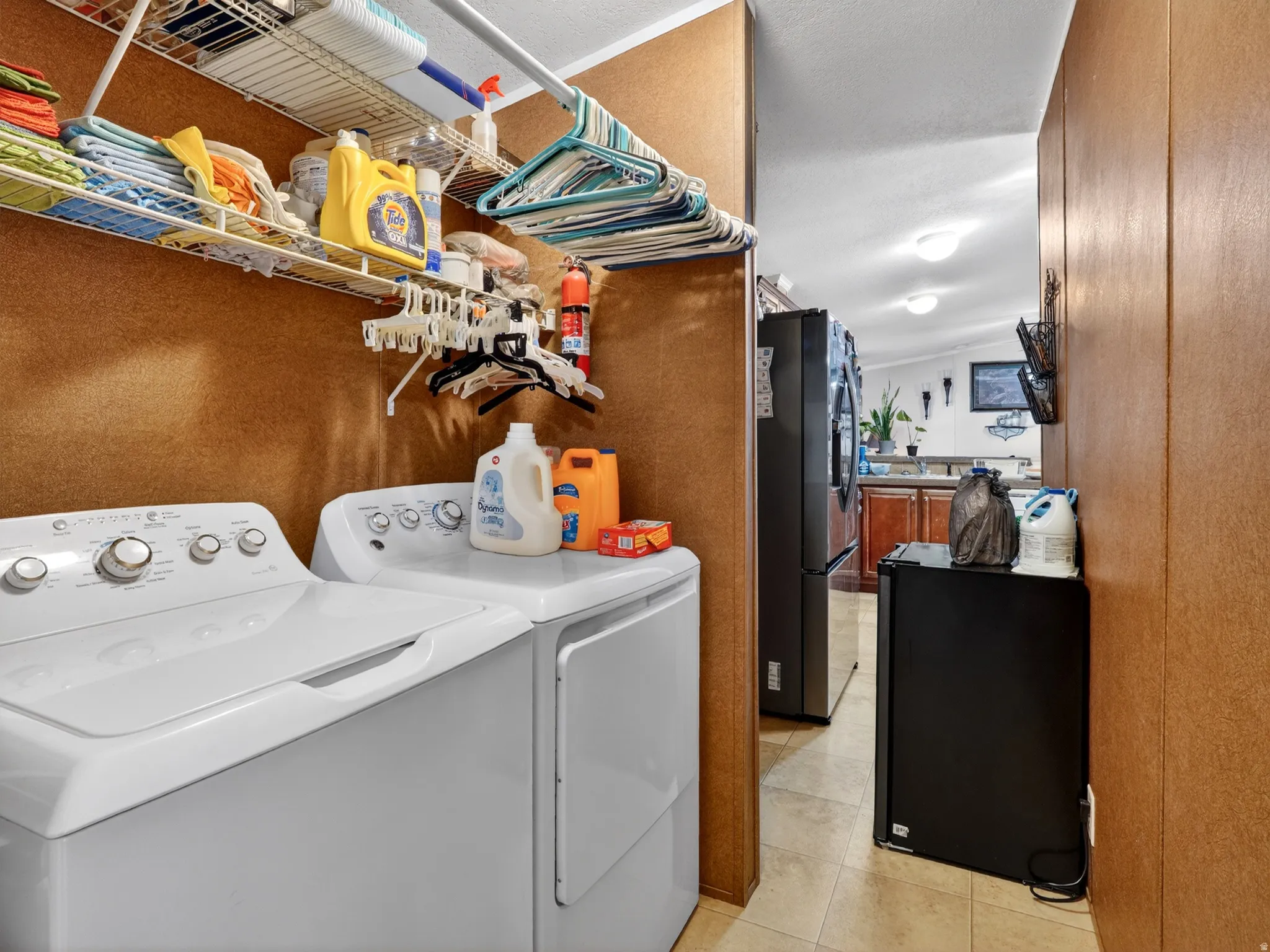 Dedicated laundry area featuring a washer and dryer, wire shelving, and wood-finish wall panels