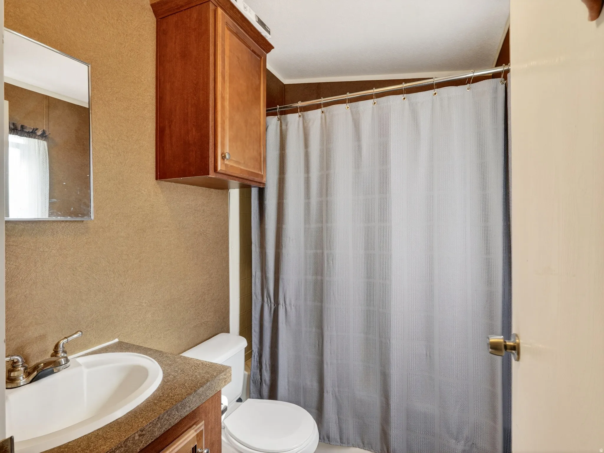 Bathroom with a built-in wood-finish vanity, a matching wood-finish wall cabinet, and a shower area with a metal shower rod