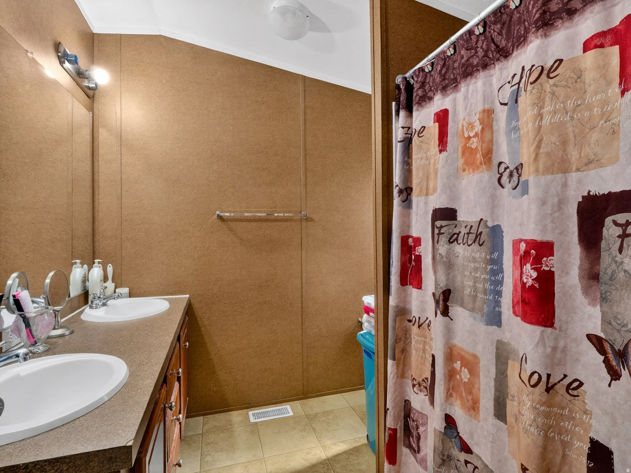 Bathroom featuring a dual vanity with integrated sinks, wood-finish cabinetry, and a full-width mirror