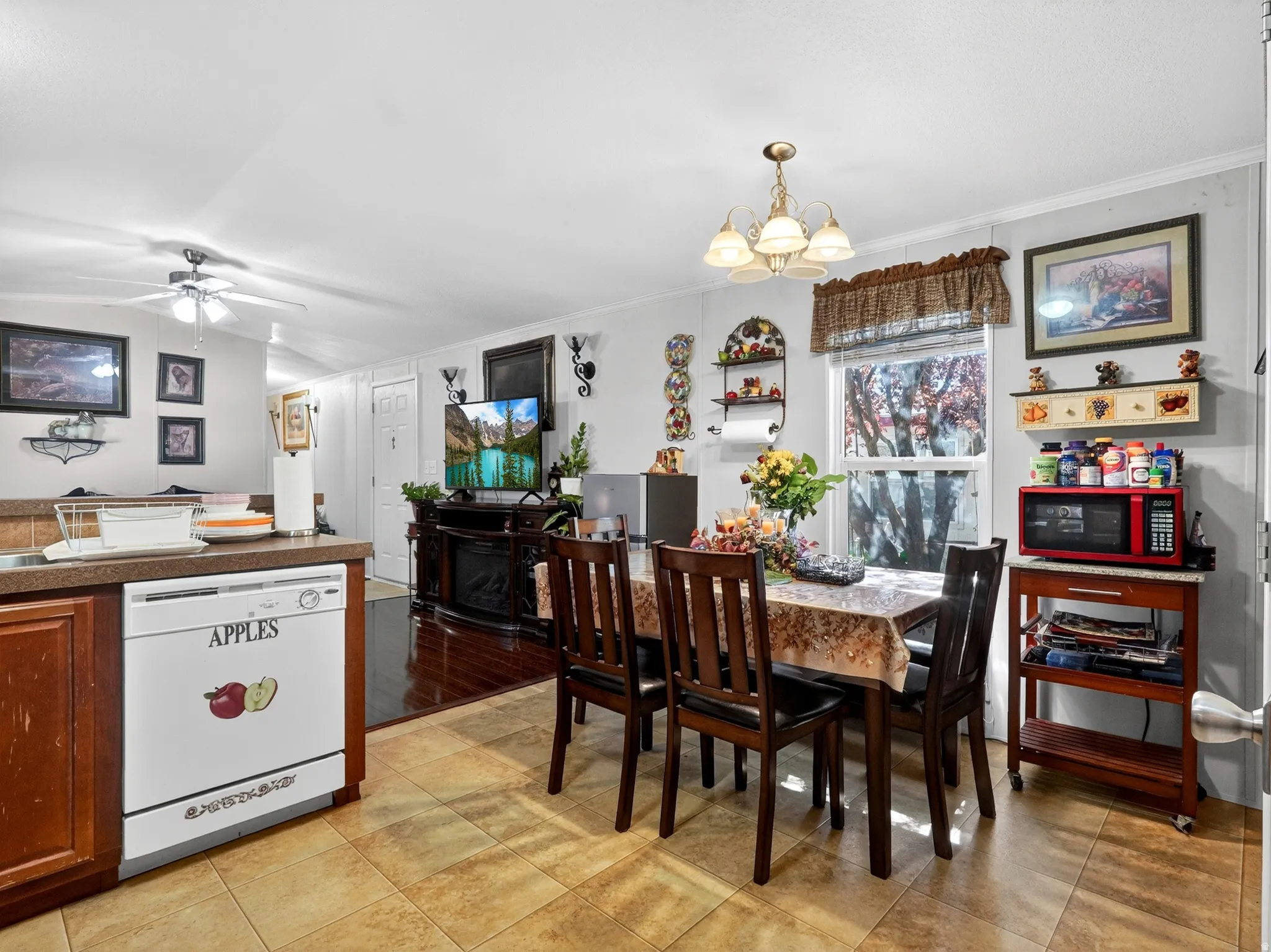 Open-concept living area featuring a dining space with a chandelier, tile flooring, and a kitchen area with wood-finish cabinetry