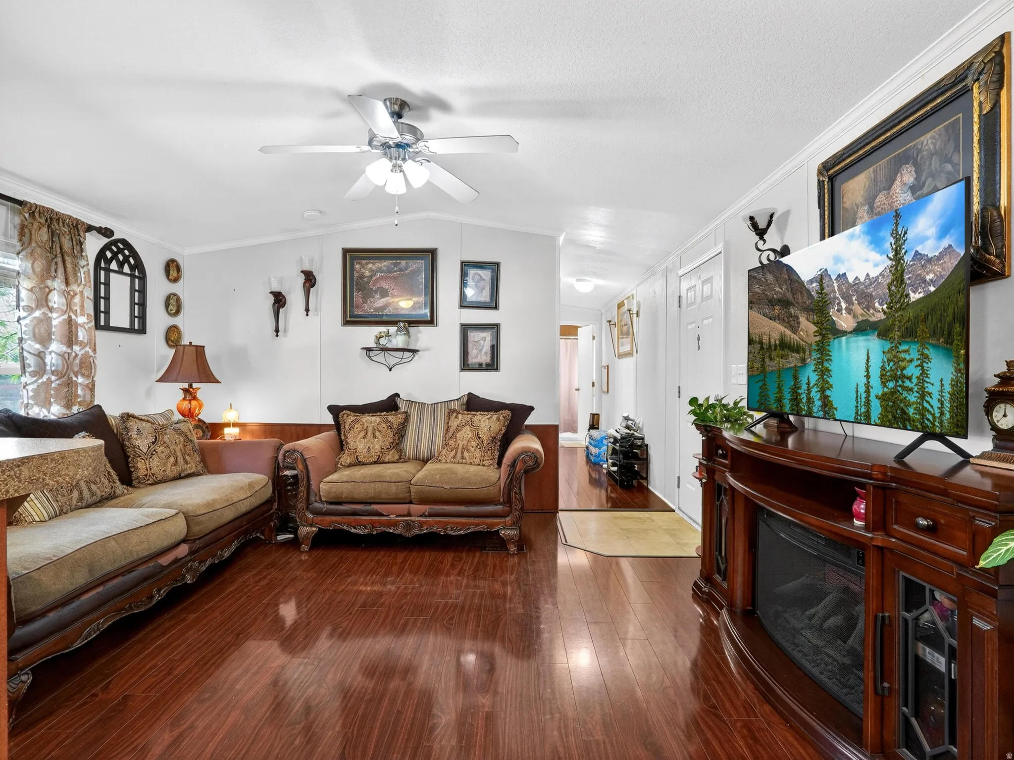 Spacious interior featuring wood-finish flooring, a ceiling fan with integrated lighting, and crown molding