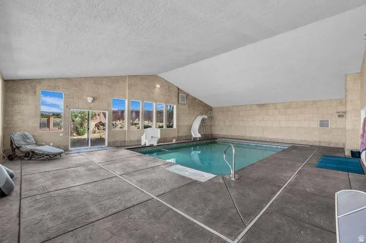 Indoor swimming pool area featuring a sloped ceiling and textured wall finishes