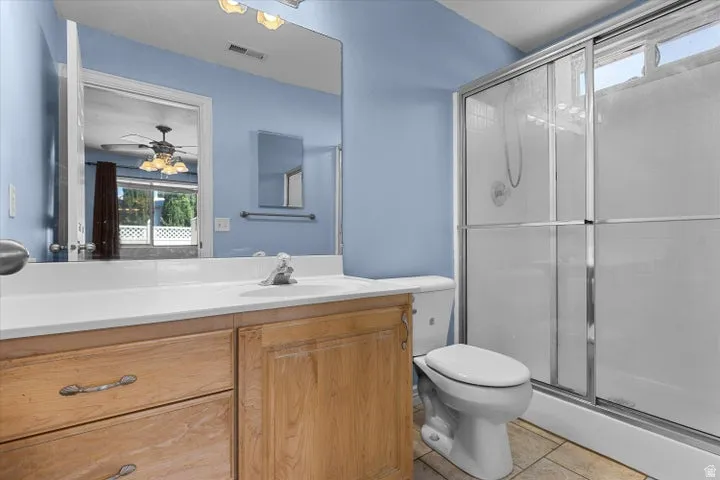 Bathroom featuring a wood-finish vanity with a white countertop and integrated sink, a large wall mirror, and a shower enclosure with sliding glass doors
