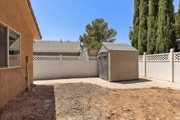 Rear yard featuring a paved area, gravel, and a shed