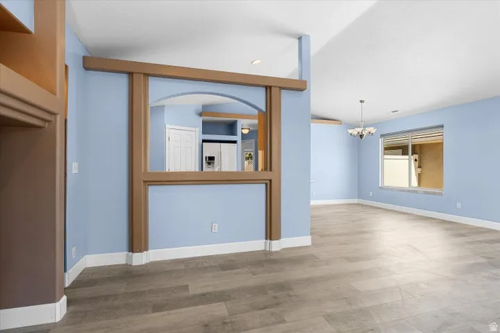 Expansive living area featuring wood-finish flooring, light blue walls, and white baseboards