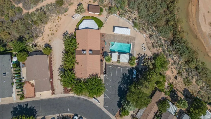 Aerial view of a property featuring a central building with a brown roof, a swimming pool, and an asphalt parking area