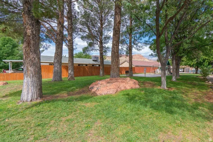 Expansive green lawn with mature trees and natural rock formations