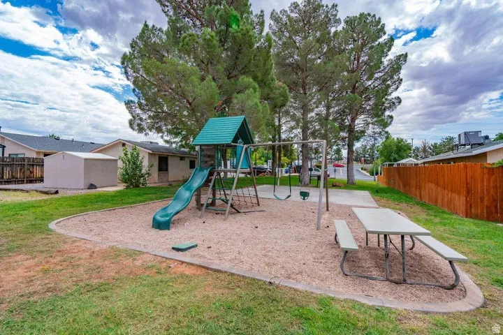 Outdoor play structure with slide and swings, surrounded by a sand base