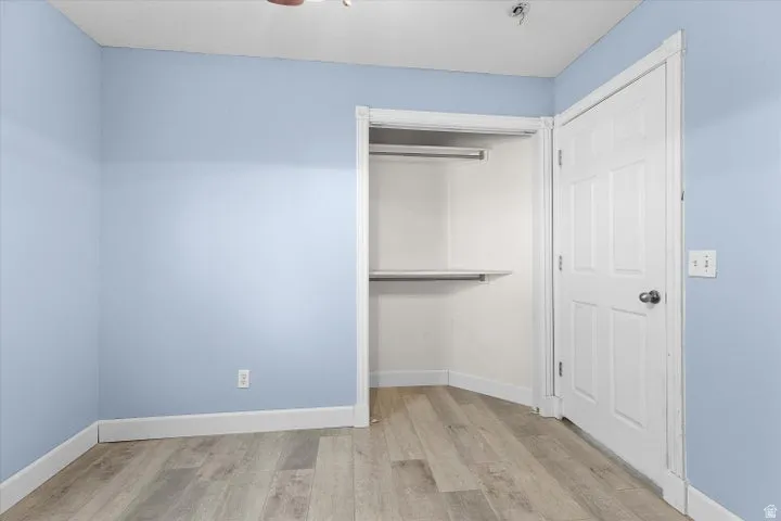 Interior room with wood-finish flooring, light blue walls, and white baseboards