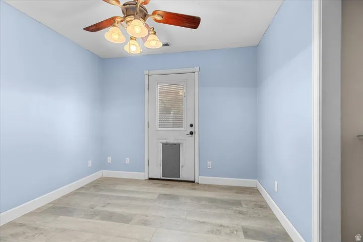Interior space with wood-finish flooring, light blue walls, and white baseboards
