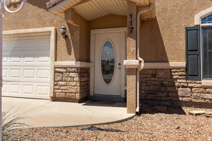 Stucco exterior with stone veneer accents, decorative garage door, and entry door with oval glass insert