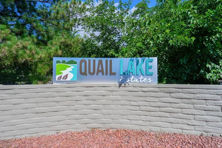 Quail Lake Estates community sign featuring a stone-stacked base, detailed graphic logo, and mature landscaping