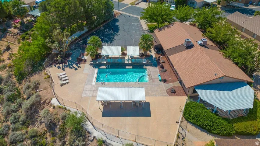 Community pool area featuring a rectangular swimming pool, an adjacent curved pool, and multiple shaded patio spaces