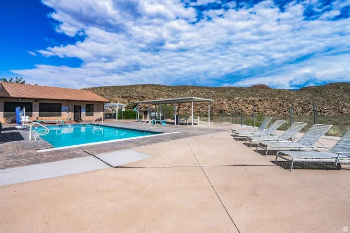 Outdoor swimming pool featuring a concrete deck surround and white grab rails