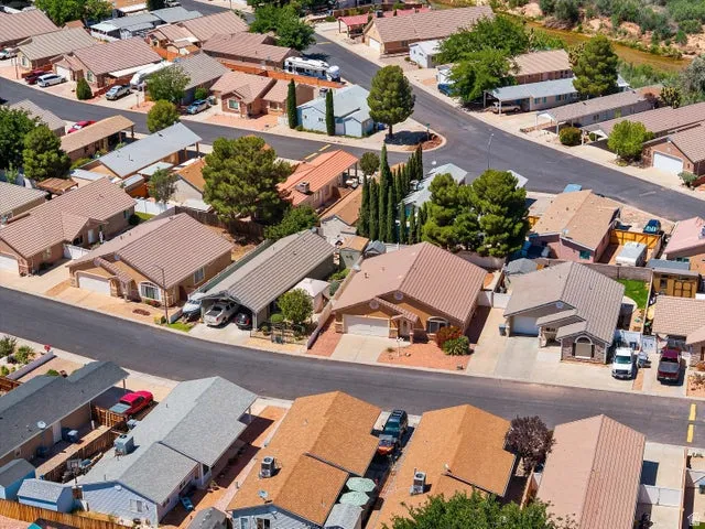 Aerial perspective of a residential community featuring single-story homes with varied rooflines and asphalt shingle or metal roofing