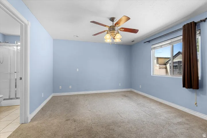 Spacious room featuring light blue walls, neutral carpet flooring, and white baseboards