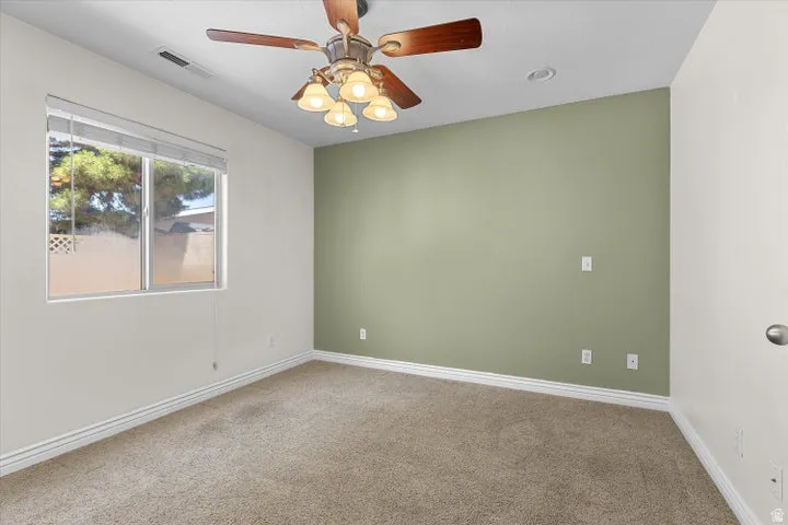 Carpeted room with a ceiling fan light fixture, recessed lighting, and a large window