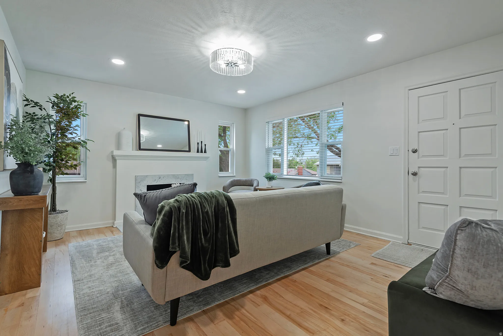Living area featuring light wood-finish flooring, recessed lighting, and a modern chandelier