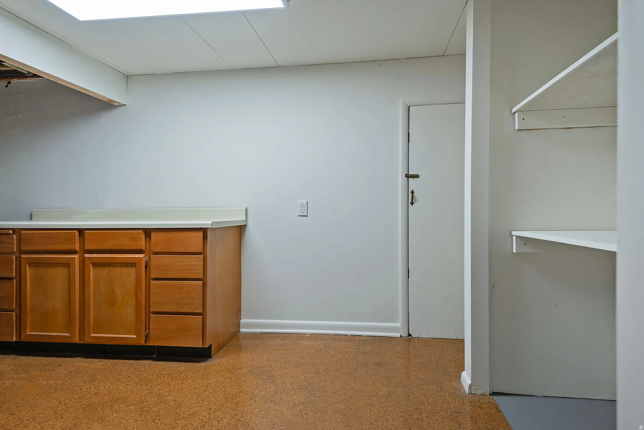 Utility room with wood cabinetry, light-toned countertop, and durable cork flooring