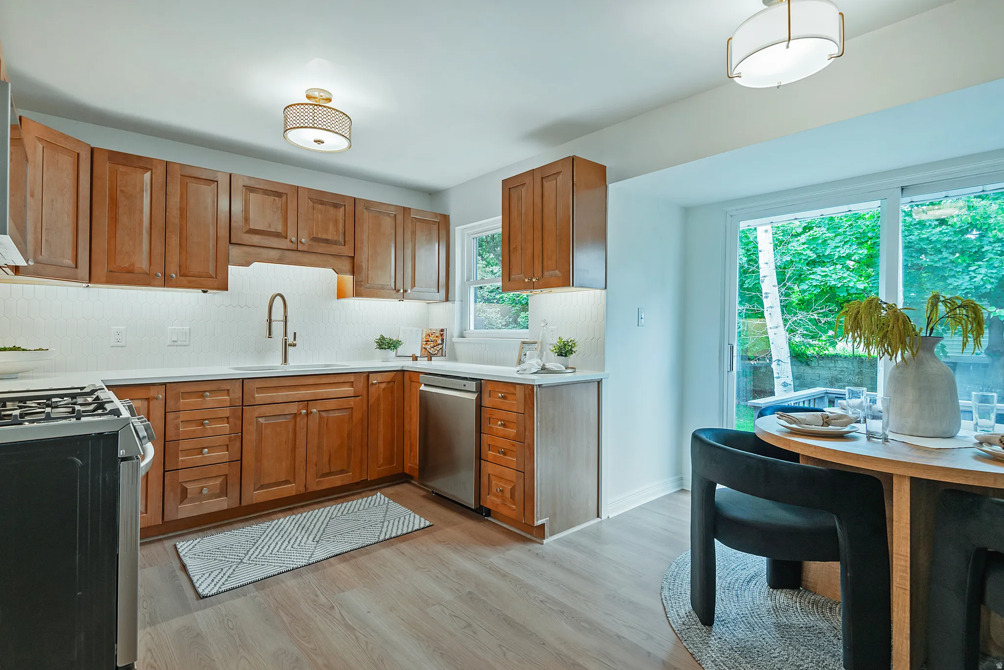 Kitchen featuring wood cabinetry, stainless steel dishwasher, white countertop, and tiled backsplash