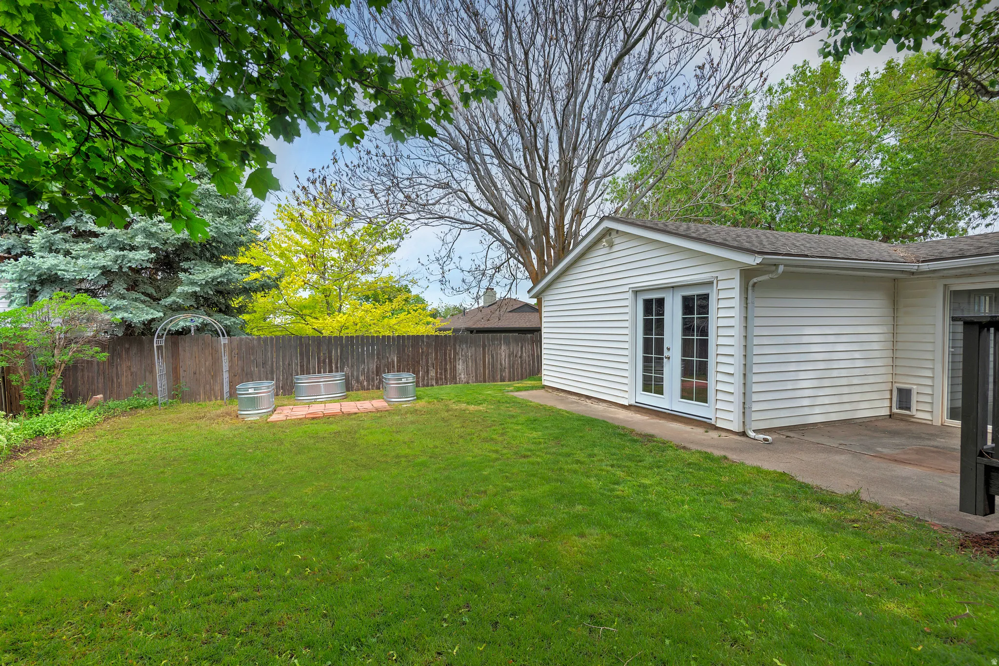 Expansive lawn with a wooden privacy fence and mature perimeter trees
