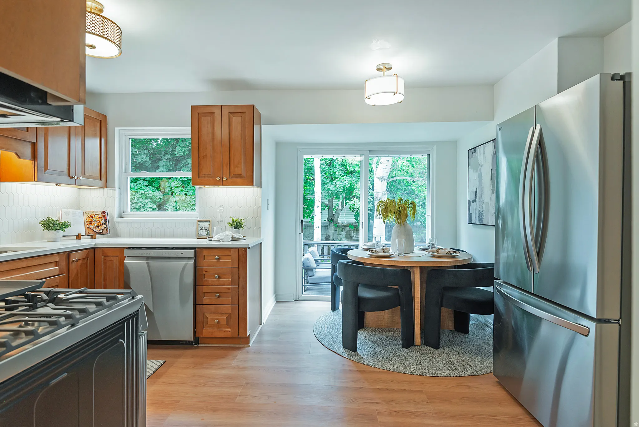 Kitchen featuring wood-finish cabinetry, stainless steel appliances, white subway tile backsplash, and wood-finish flooring