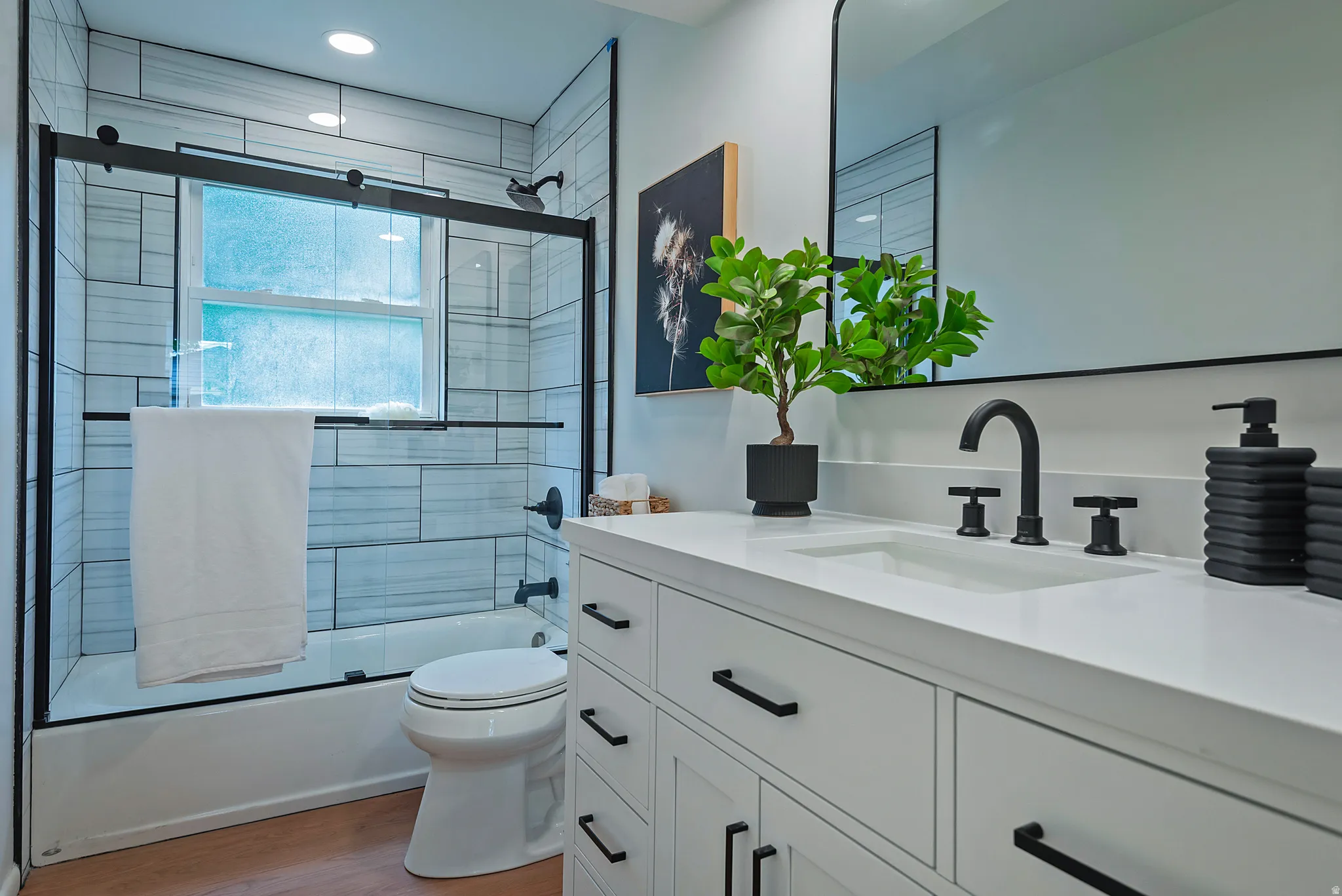 Modern bathroom featuring a white vanity with matte black hardware, a recessed rectangular sink, and a black-framed mirror