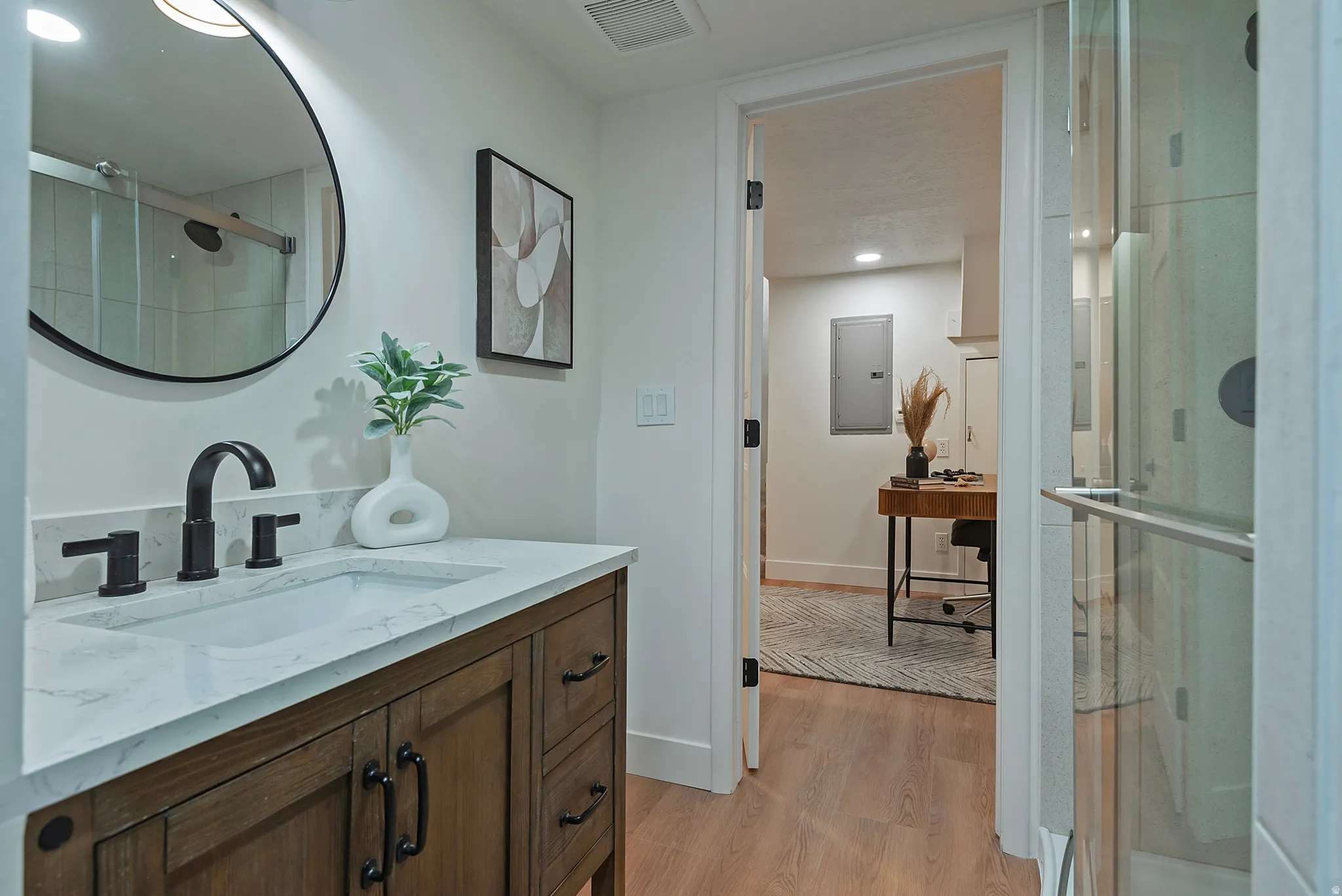 Bathroom vanity featuring a quartz countertop, matte black fixtures, and wood-finish cabinetry