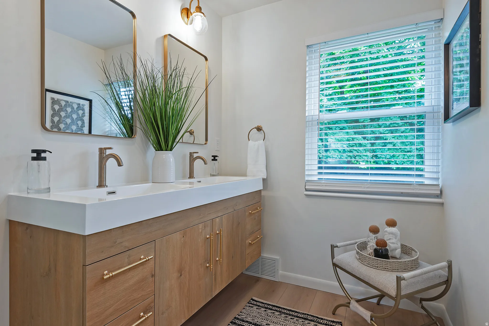 Double vanity with integrated sinks, wood-finish cabinetry, and gold-toned hardware