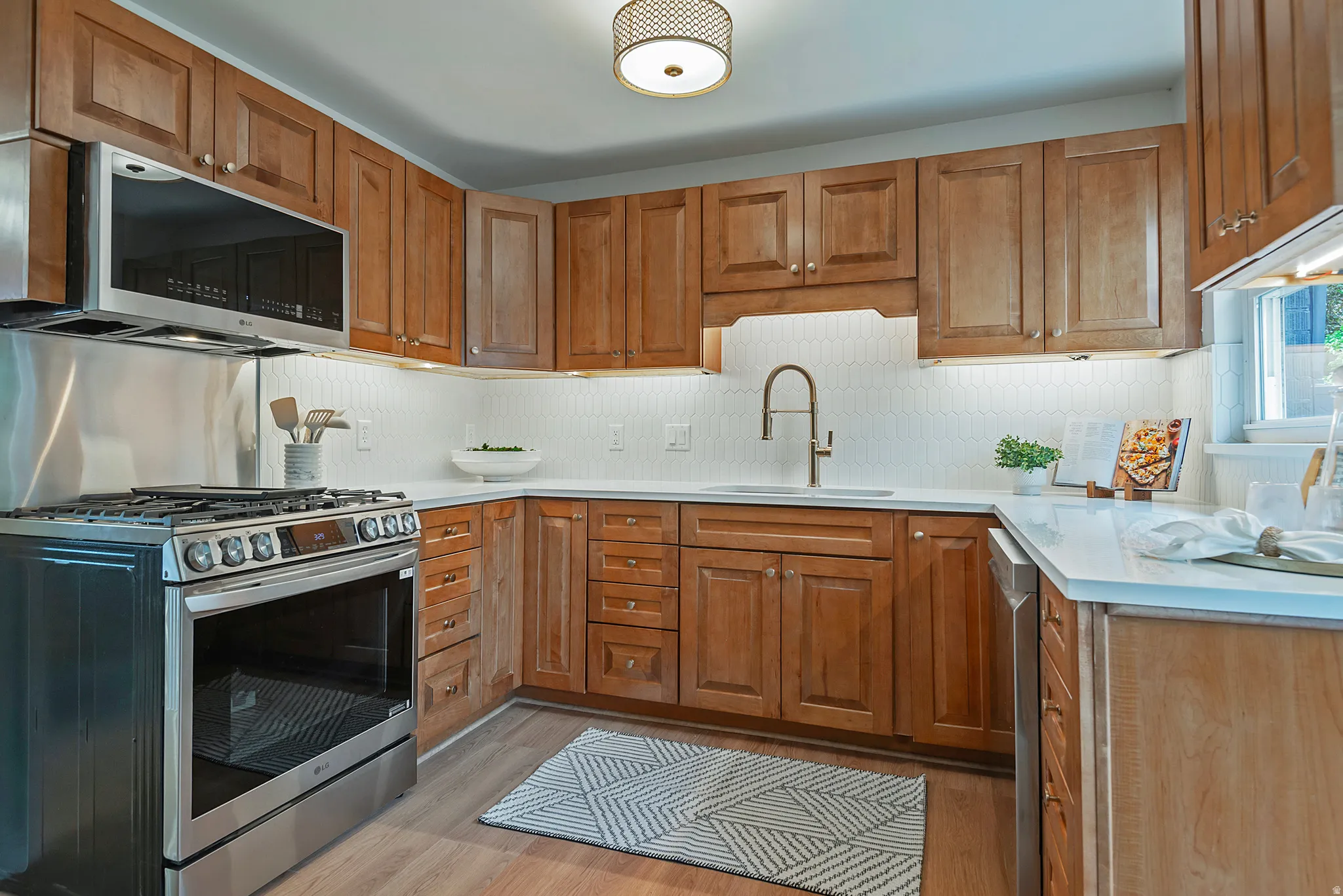 Kitchen featuring wood cabinetry, stainless steel appliances, white countertops, and a white tiled backsplash