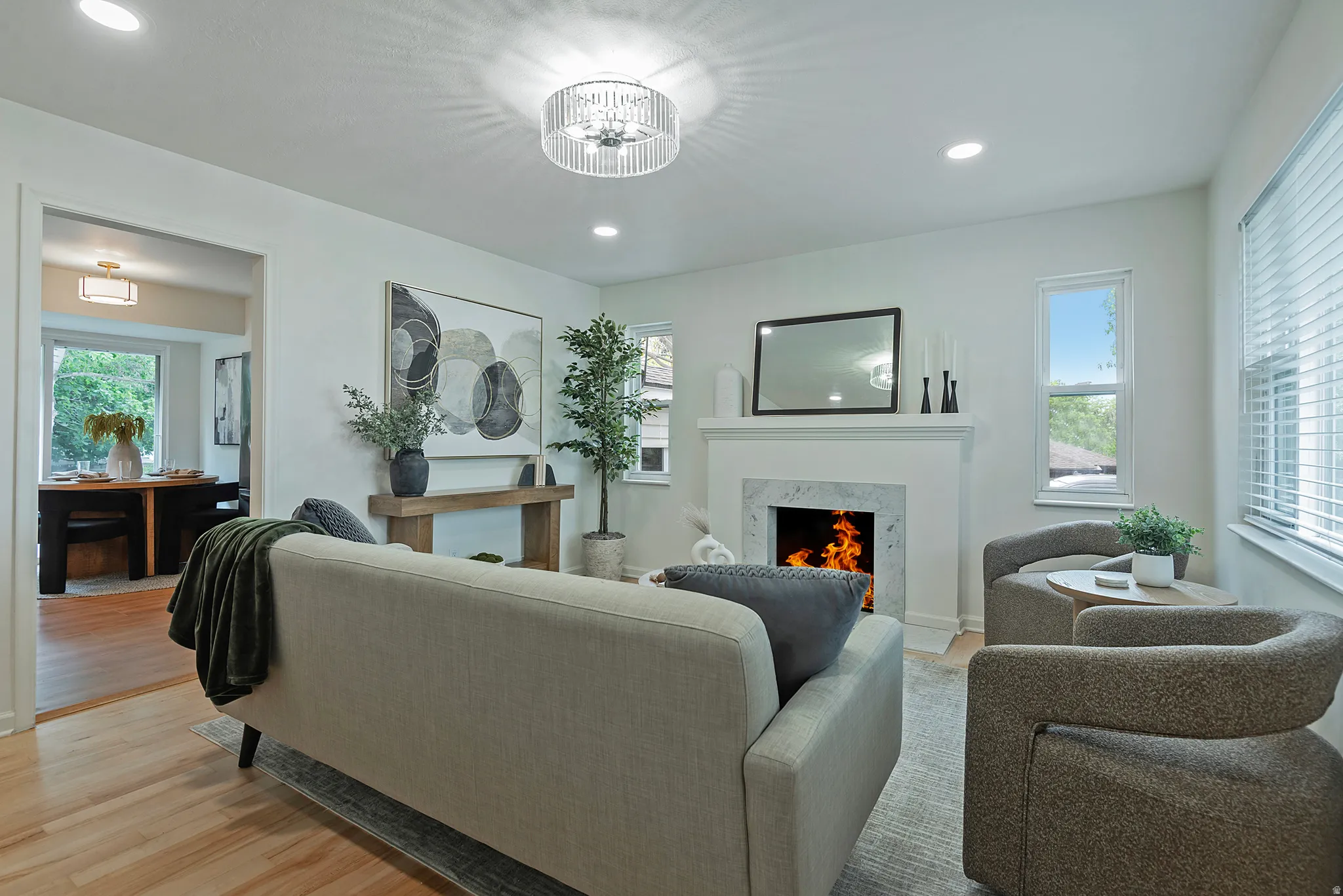 Bright living space featuring a white mantel fireplace with a stone surround, recessed lighting, and wood-finish flooring