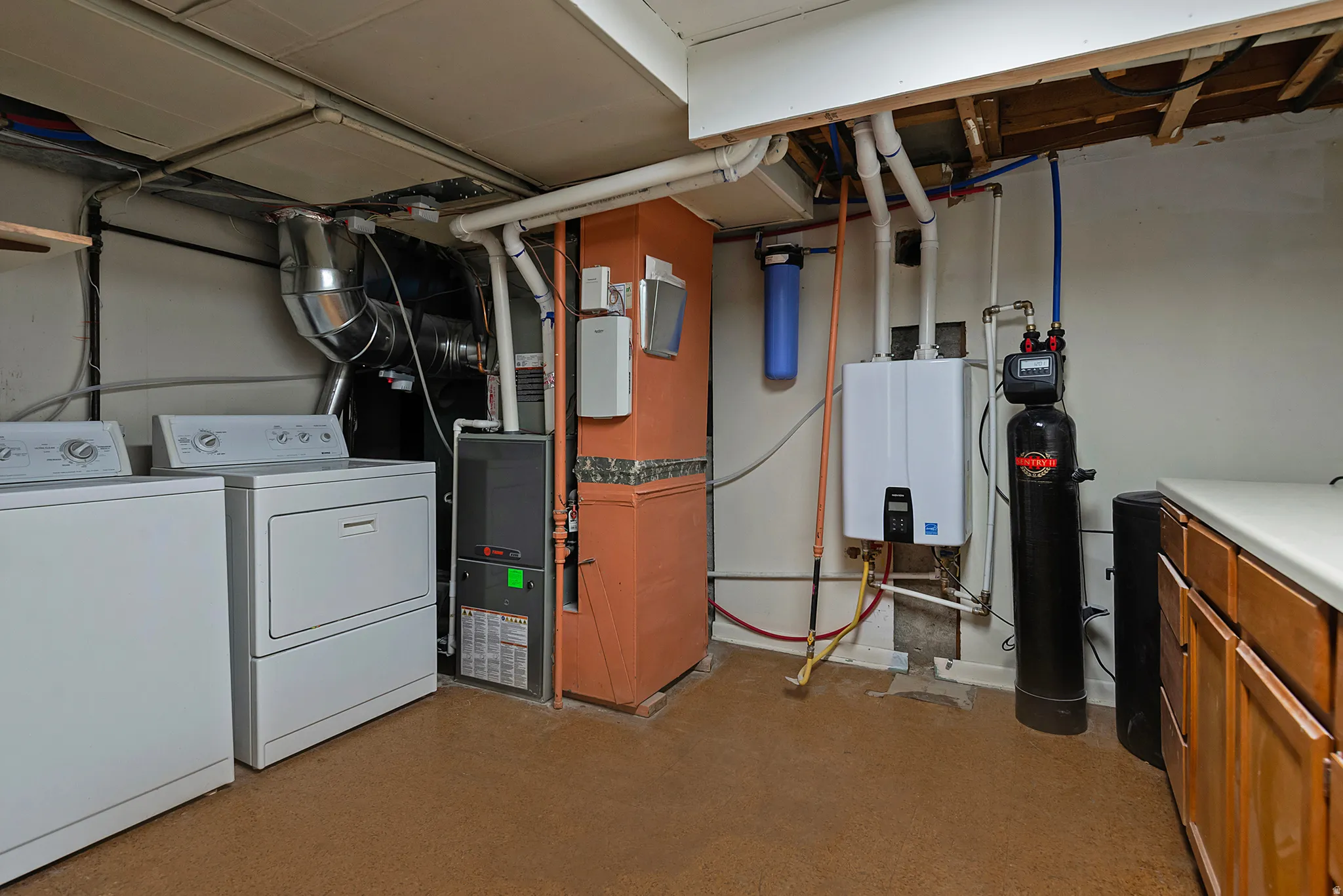 Utility area featuring a water filtration system, tankless water heater, and a furnace