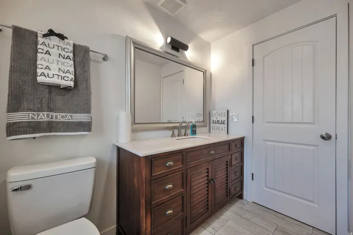 Bathroom featuring a wood-finish vanity with a light-toned countertop and an undermount sink