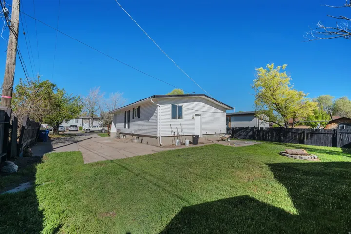 Expansive backyard featuring a manicured lawn, concrete patio, and privacy fencing