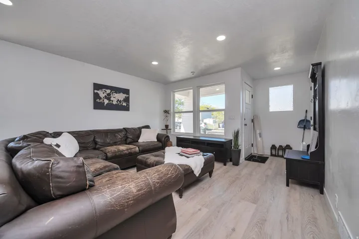 Bright living area featuring wood-finish flooring, recessed ceiling lighting, and multiple windows