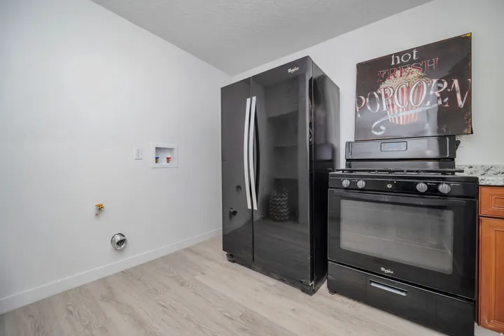Kitchen area featuring a black gas range with an overhead vent and a side-by-side refrigerator