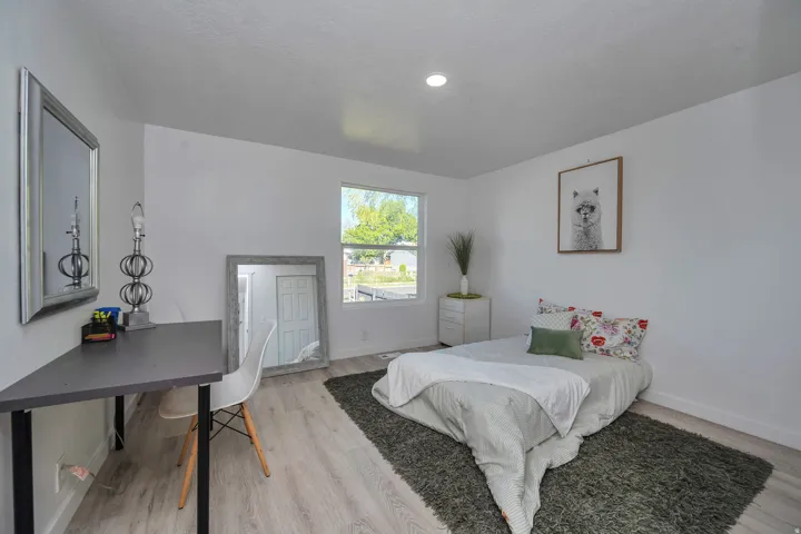Bright interior space featuring light wood-finish flooring, a single window providing natural light, and a white ceiling with recessed lighting