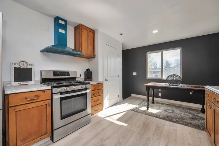 Kitchen featuring light wood-finish flooring, stainless steel range and oven, and a contemporary blue range hood