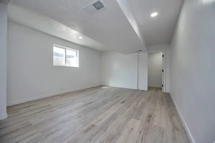 Spacious room featuring wood-finish flooring, recessed lighting, and a white trim window