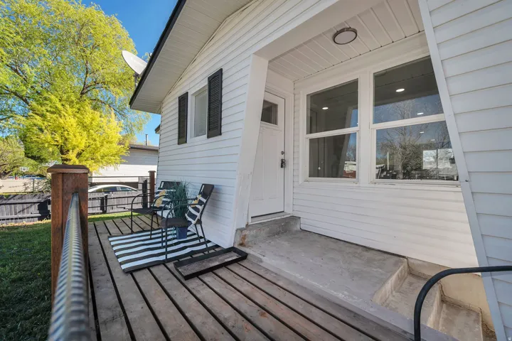 White exterior siding featuring a wooden deck with a black metal railing