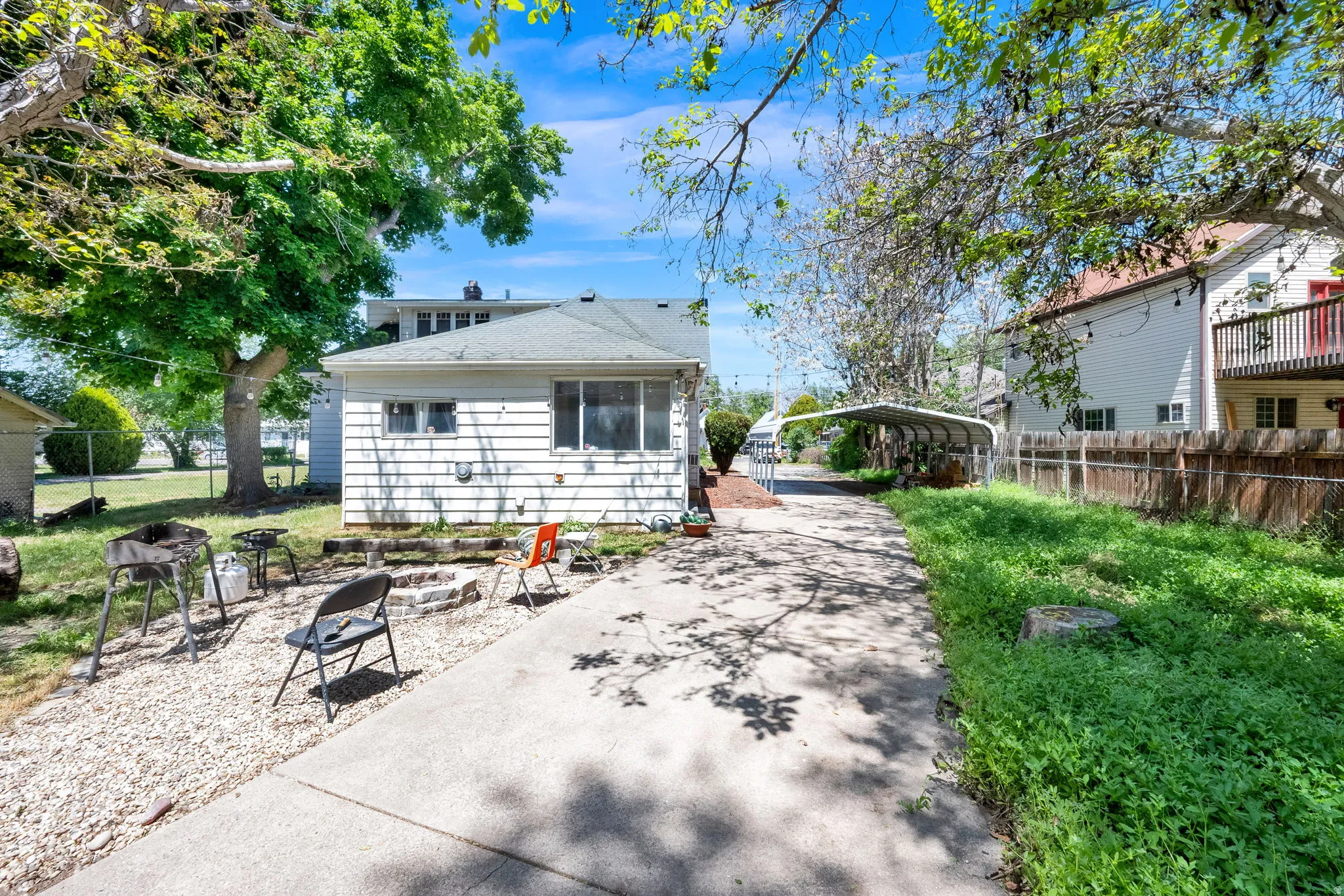 Spacious concrete driveway featuring an adjacent gravel patio area